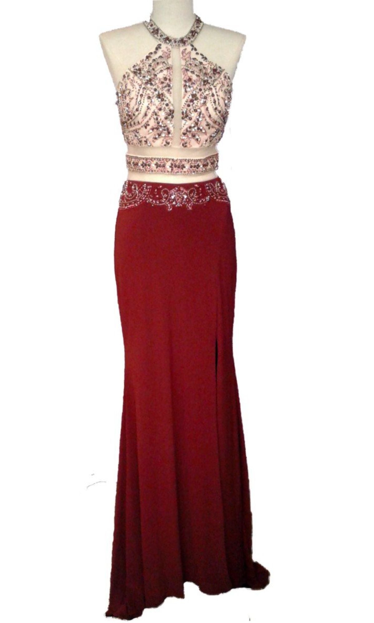 The Chicas CR7001 Faux Two-Piece Long Prom Dress is a sleeveless red gown with a jeweled halter neckline, beaded bodice, sheer midriff, and floor-length skirt shown on a mannequin.